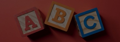 Three wooden A, B and C blocks in red, orange and blue on a red background