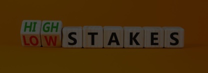 Wooden blocks spelling the words high and low stakes on an orange background