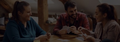 four diverse young people learning to play a card game together