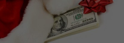An image of a wad of dollar bills with a red bow and a Santa hat on a white background