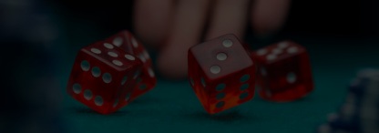 An image of a hand rolling dice on a poker table with blurred stacks of poker chips on