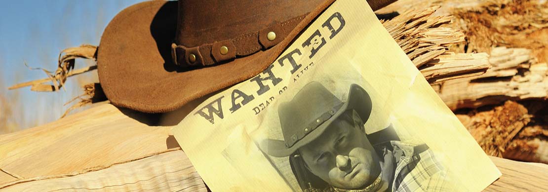 cowboy hat on a lot with a vintage Wanted poster