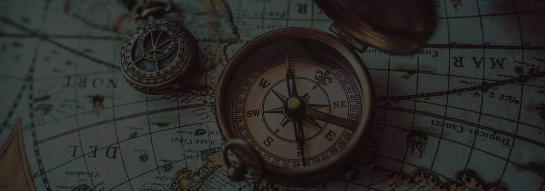 antique bronze compass sitting on an old map