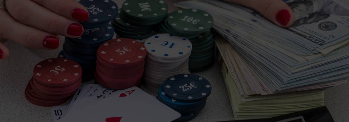 A photo of a calculator poker chips, dash and cards on a poker table with a woman's hands on them.