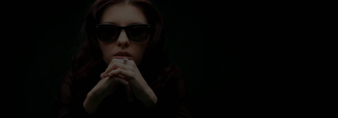 a female poker player in deep thought and with sunglasses so the others can't see that she is watching everything