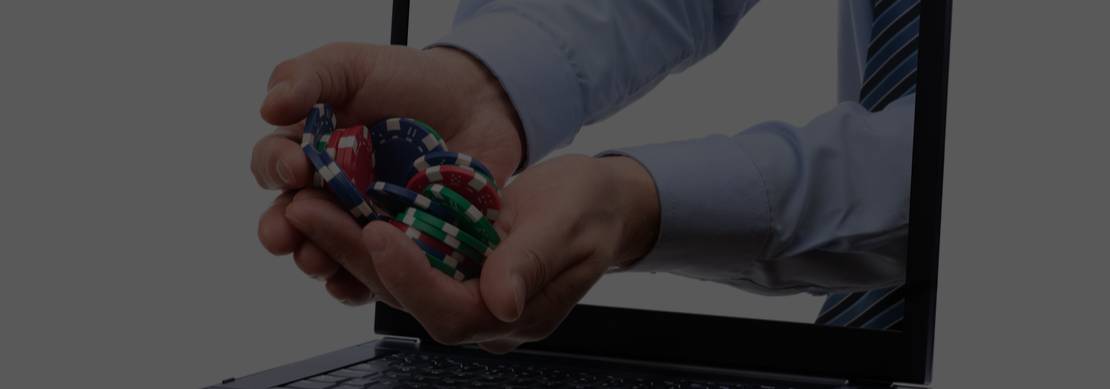 A laptop screen with two hands coming out of it holding colorful poker chips