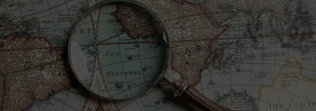 a magnifying glass against an old map indicating the tools of the trade of explorers from long ago