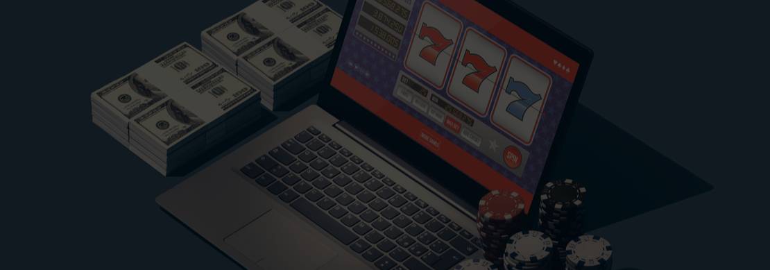 An illustration of an open laptop displaying a 3-reel slot with casino chips and money stacks next to it on a blue background