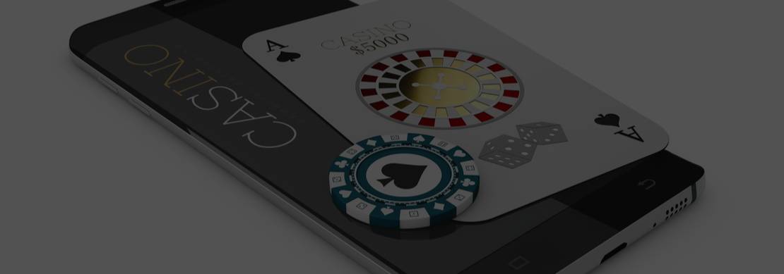 A playing card and casino chip on top of a mobile phone with the word ‘Casino’ on the screen on a white background