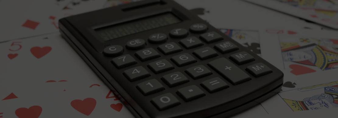 a pocket calculator set on a background of playing cards strewn about on a table indicating the challenge of math in poker