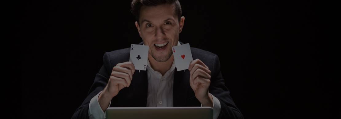 poker player sitting at a poker table with a laptop, chips and cards