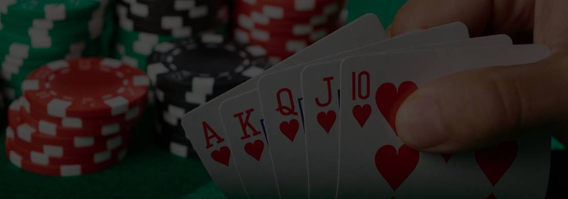 Person holding a royal flush hand of cards with stacks of casino chips on a poker table