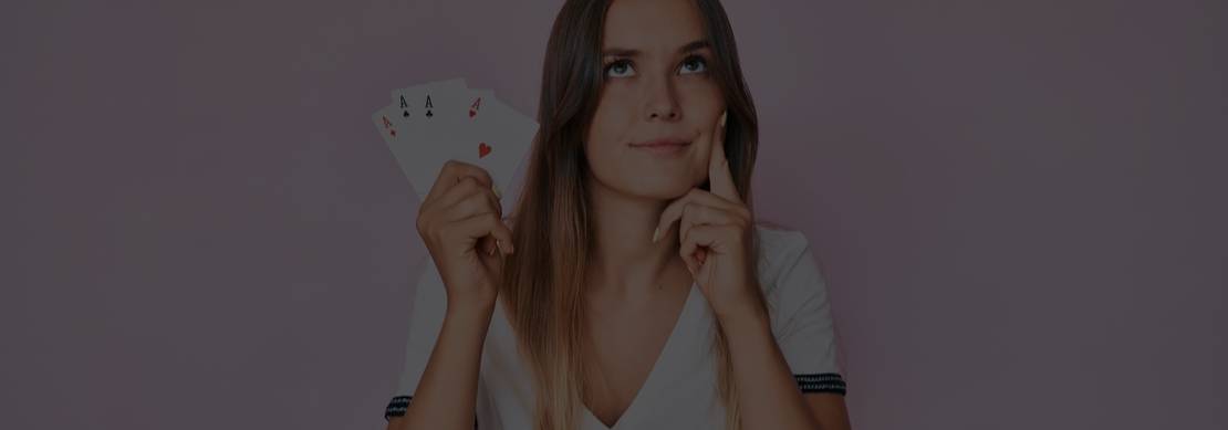 attractive woman with white top and long brown hair contemplating her next bet with four aces