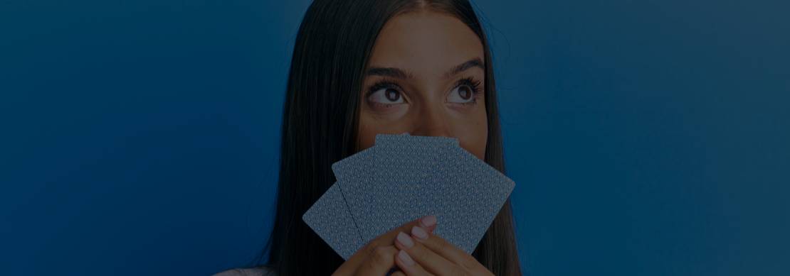 young woman with long straight dark hair looking away from her cards as she thinks about her next move